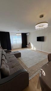 a living room with a couch and a flat screen tv at RentHouse Samal in Astana