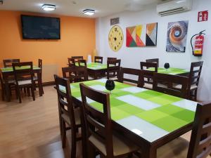 ein Esszimmer mit Tischen und Stühlen und einem Fernseher in der Unterkunft Hostal T4 in Paracuellos de Jarama