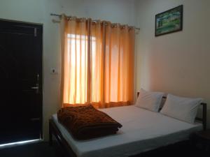 a bed in a bedroom with an orange curtain at Mountain View Cottage Shivpuri Rishikesh in Rishīkesh