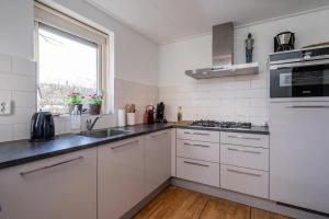a kitchen with white cabinets and a sink and a window at Christoffellaan 57 in Brouwershaven