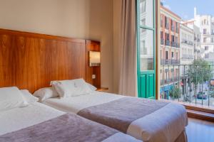 a hotel room with two beds and a window at Ateneo Puerta del Sol in Madrid