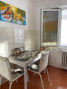 a dining room table with chairs and a painting on the wall at ELENA Center Apartment in Timişoara