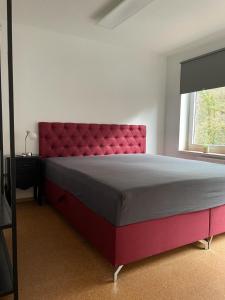 a bedroom with a large bed with a red headboard at Bad Salzdetfurth Gästewohnungen in Bad Salzdetfurth