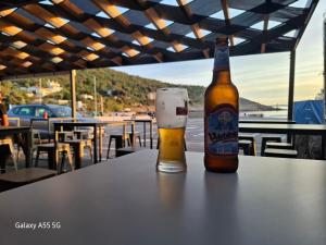 a bottle of beer sitting on a table with a glass at Studio Apartman Zlata in Stinica