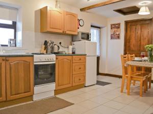 a kitchen with wooden cabinets and a white stove top oven at Dairy Cottage in Marros