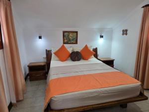 a bedroom with a large bed with orange pillows at The Drake Seaside Apartment in Bel Ombre +44 photos