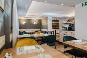 a restaurant with wooden tables and green chairs at Hotel St. Michael in Livigno