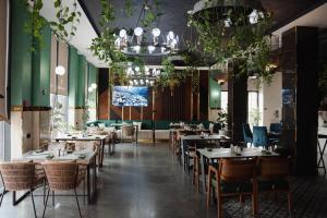 a dining room with tables and chairs and plants at Cosmopolitan Hotel in Shymkent