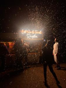 a man walking in front of a sign at night at Beer Base-Camp Oktoberfest camping with free welcome beer and traditional dirndl-lederhosen shop in Munich +32 photos