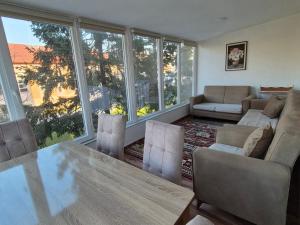 a living room with a table and chairs and windows at Eloi Apartment in Gjakove