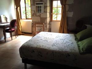 a bedroom with a bed and a desk and windows at La Closerie in Saint-Philbert-du-Peuple