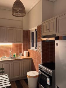 a kitchen with white cabinets and a sink and a refrigerator at Psani 50m2 apartment in Nafpaktos +5 photos
