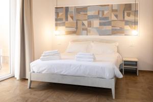a bedroom with a white bed with a painting on the wall at Guest house - L'amante e il marinaio in Fiumicino