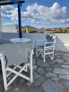 a white table and chairs on a stone patio at Peaceful Cycladic Studio with Large Terrace & View in Tripiti +6 photos