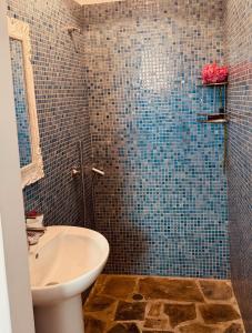 a bathroom with a sink and a shower with blue tiles at Peaceful Cycladic Studio with Large Terrace & View in Tripiti