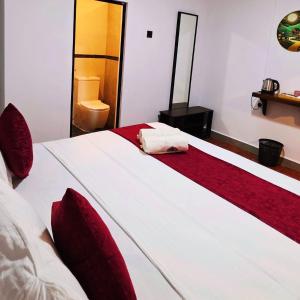a bedroom with a large white bed with red pillows at French garden Pragash Beach Hotel in Trincomalee