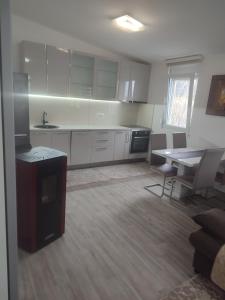 a kitchen with white cabinets and a table and chairs at Bar ,2 sobni stan ,Namaste ! in Bar +12 photos