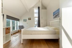 a white bedroom with a bed and a window at Villa Beach & Spa in Julianadorp