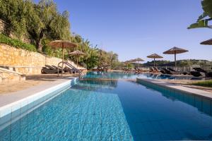 a swimming pool with blue water and umbrellas at Mary's Panorama Houses in Gialova