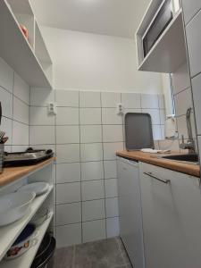 a small kitchen with white tiled walls and a counter at Gesztenyés Üdülő in Balatonudvari
