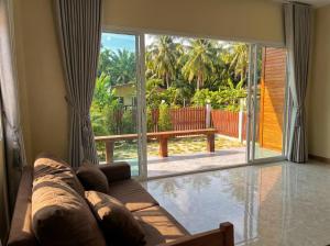 a living room with a couch and a large sliding glass door at The Triangle Villas in Srithanu