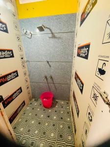 a bathroom with a shower with a red bucket at Avenue Dorms in Kalpetta