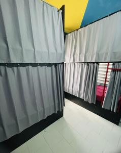 a bathroom with grey curtains and white tiles at Avenue Dorms in Kalpetta
