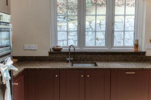 a kitchen with a sink and two windows at Grey Walls in Penrith +29 photos