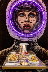a table with plates of food and a painting of a woman at Fairytale Athens - Luxury Suites in Athens +29 photos
