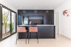 a kitchen with black cabinets and pink bar stools at Villa Palmera in San Javier