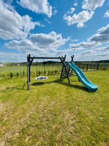 a playground with a blue slide in a field at Słoneczny Pagórek in Giżycko