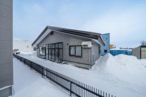 a house in the snow with a fence at Prunoia in Furano
