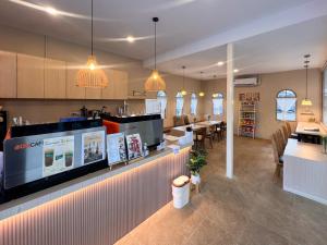 a restaurant with a counter and a bar with chairs at Baan Mak Mai Hotel in Si Sa Ket