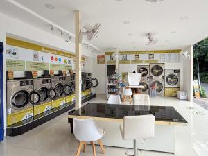 a laundry room with several washing machines and chairs at Baan Mak Mai Hotel in Si Sa Ket