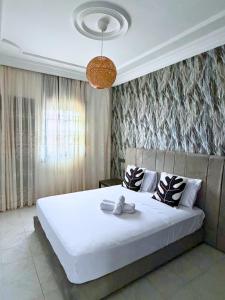 a bedroom with a large white bed and a chandelier at 2 chambres tout confort - calme absolue in Temara
