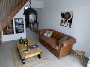 a living room with a brown leather couch and a table at Cozyhouse in Touquet Berthe