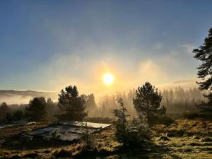 a misty sunrise on a mountain with a cabin at Glenshee Suite, Beechtree Cottage in Kirkmichael
