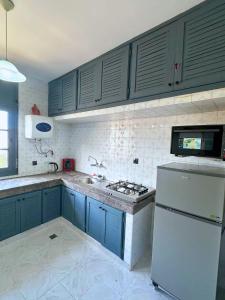a kitchen with blue cabinets and a white refrigerator at 2 chambres tout confort - calme absolue in Temara