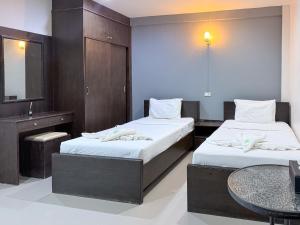 a bedroom with two beds and a sink and a table at Baan Mak Mai Hotel in Si Sa Ket
