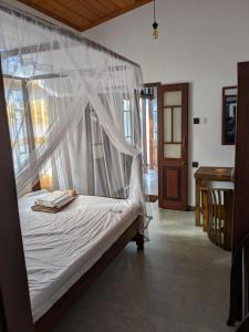 a bedroom with a bed with a mosquito net at Mango Tree Weligama in Weligama