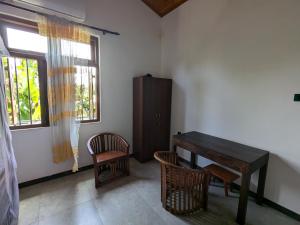 a dining room with a wooden table and two chairs at Mango Tree Weligama in Weligama