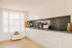 a kitchen with white cabinets and a counter top at Blue Ark, villa vue mer avec piscine, idéale en famille face à Gibraltar in Manilva