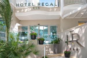 a hotel lobby with potted plants and a hotel rental sign at Hotel Regal in Rimini