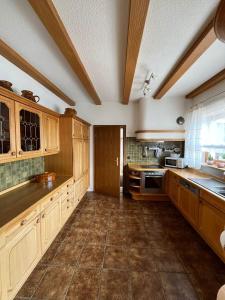 a large kitchen with wooden cabinets and tile floors at Ferienhaus Altenplos in Heinersreuth