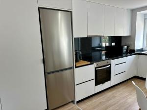 a kitchen with white cabinets and a stainless steel refrigerator at Cantinho da Nina in Arcos de Valdevez