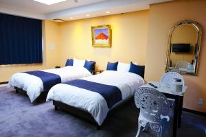 a hotel room with two beds and a mirror at ゲストハウス 清水銀座 in Shizuoka
