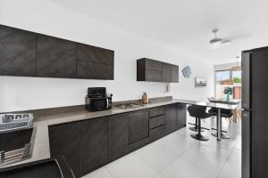 a kitchen with brown cabinets and a table in it at Rooftop & Jacuzzi privé à 5 min de la plage in Flic-en-Flac