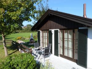 a cottage with a patio with chairs and a fountain at Chiemsee Comfort-Bungalow mit Garten in Rimsting