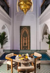 a dining room with a table and chairs and a chandelier at Riad Secret De Medina in Marrakesh