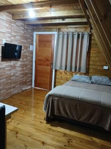 a bedroom with a bed and a flat screen tv at Chalés Snow in Urubici
